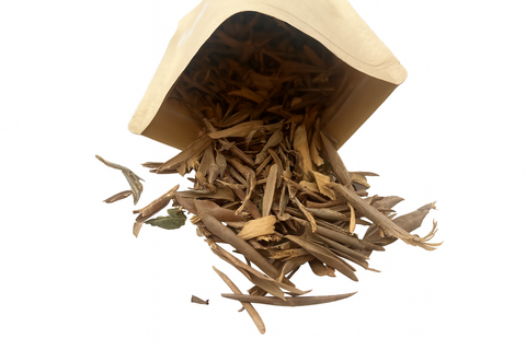 Bolsa de papel kraft volcada mostrando el contenido de forrajeo natural con abundantes ramitas y hojas de olivo para aves.