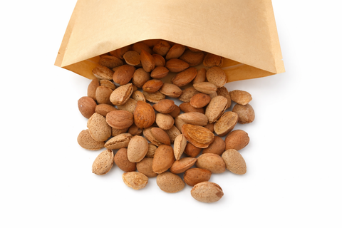 Almendras naturales con cáscara para loros saliendo de bolsa de papel kraft