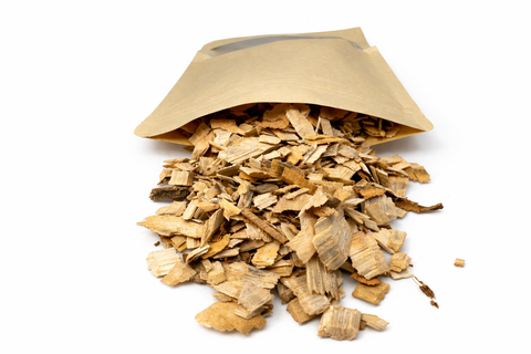 Madera de laurel triturada natural saliendo de bolsa kraft, sin tratamientos ni aditivos, utilizada como material vegetal para forrajeo y base higiénica en voladeras de aves.